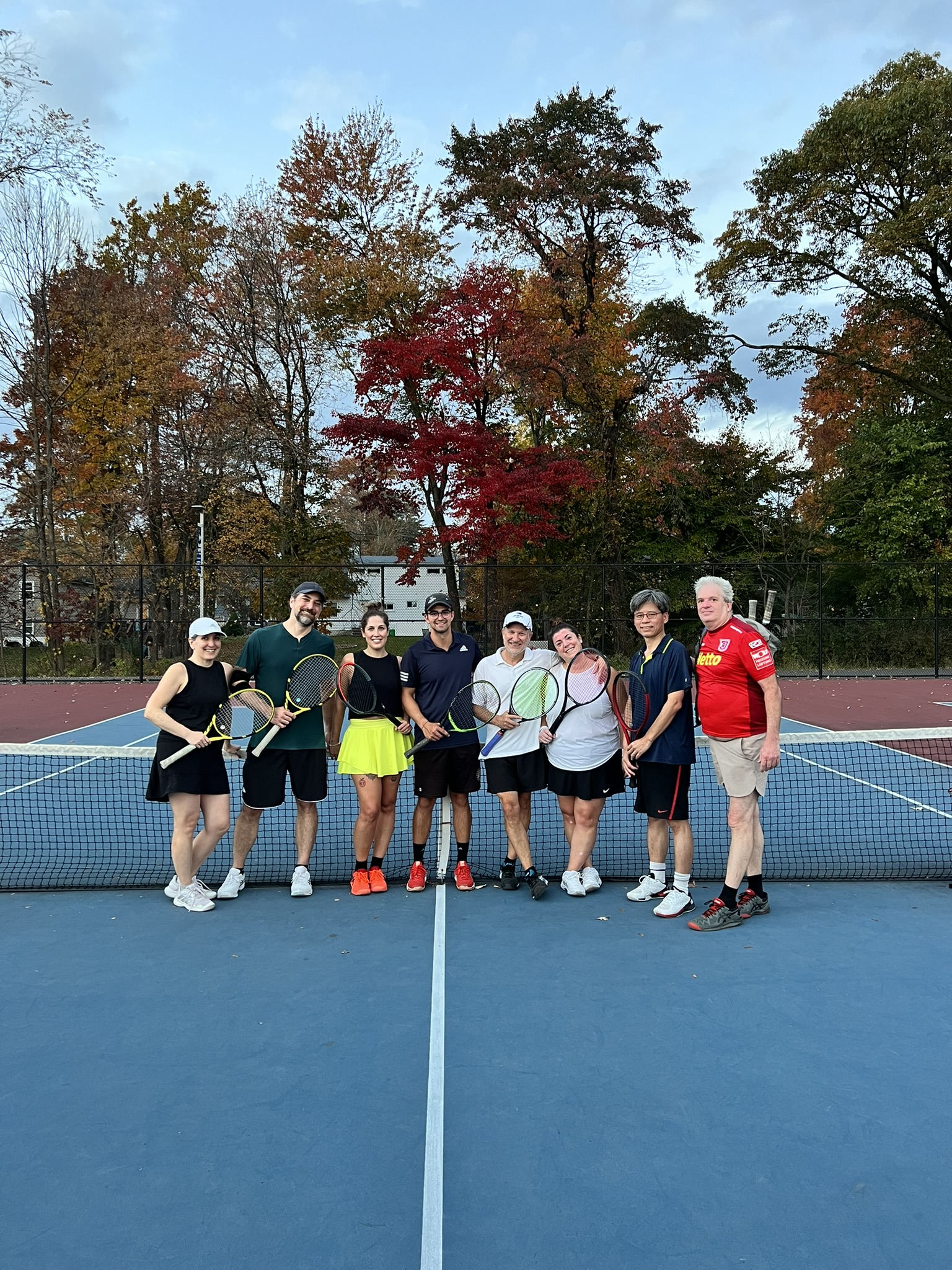Adult tennis players and coaches together on court