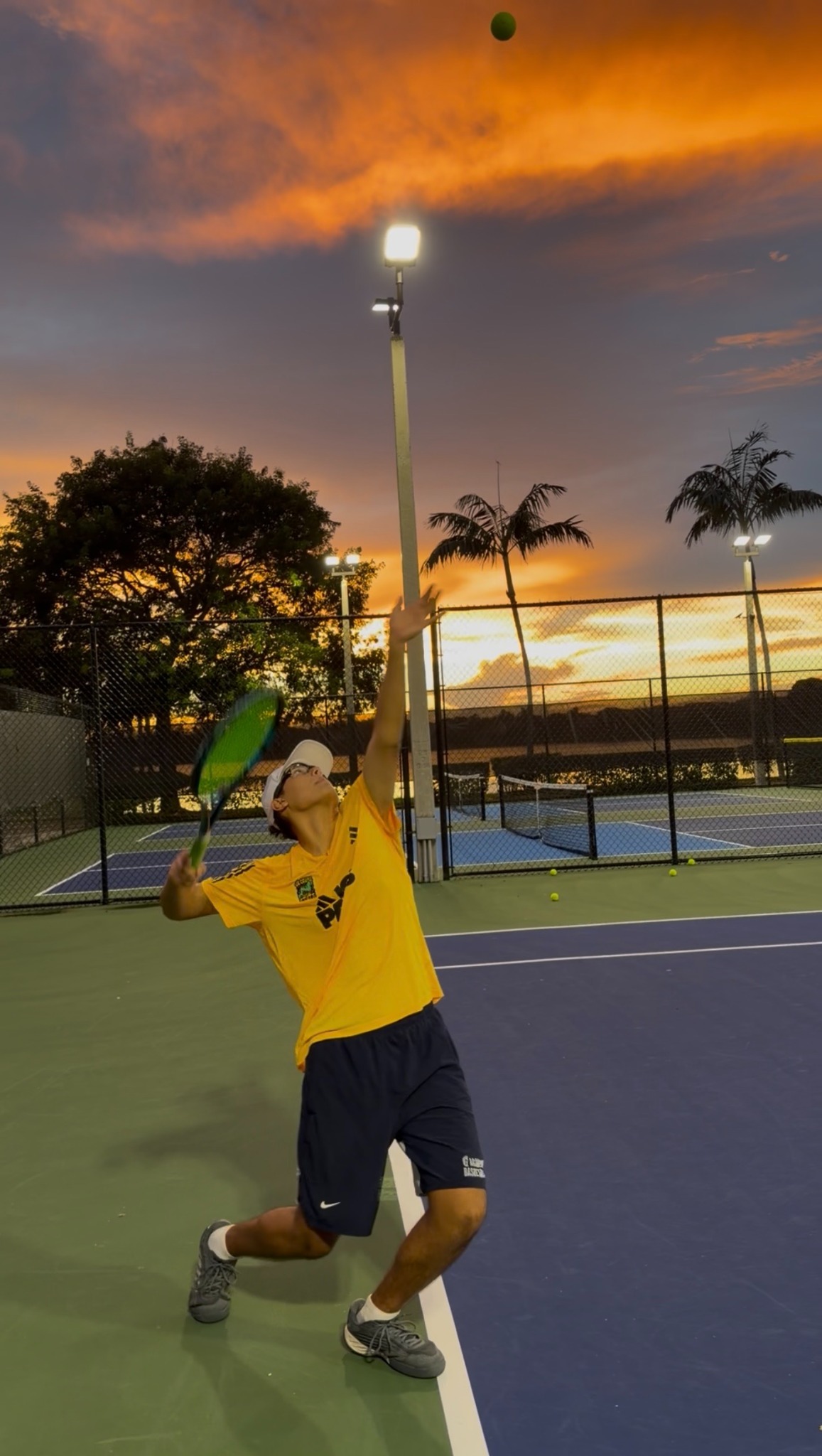 Alexander Ramey practicing his serve on court at sunset